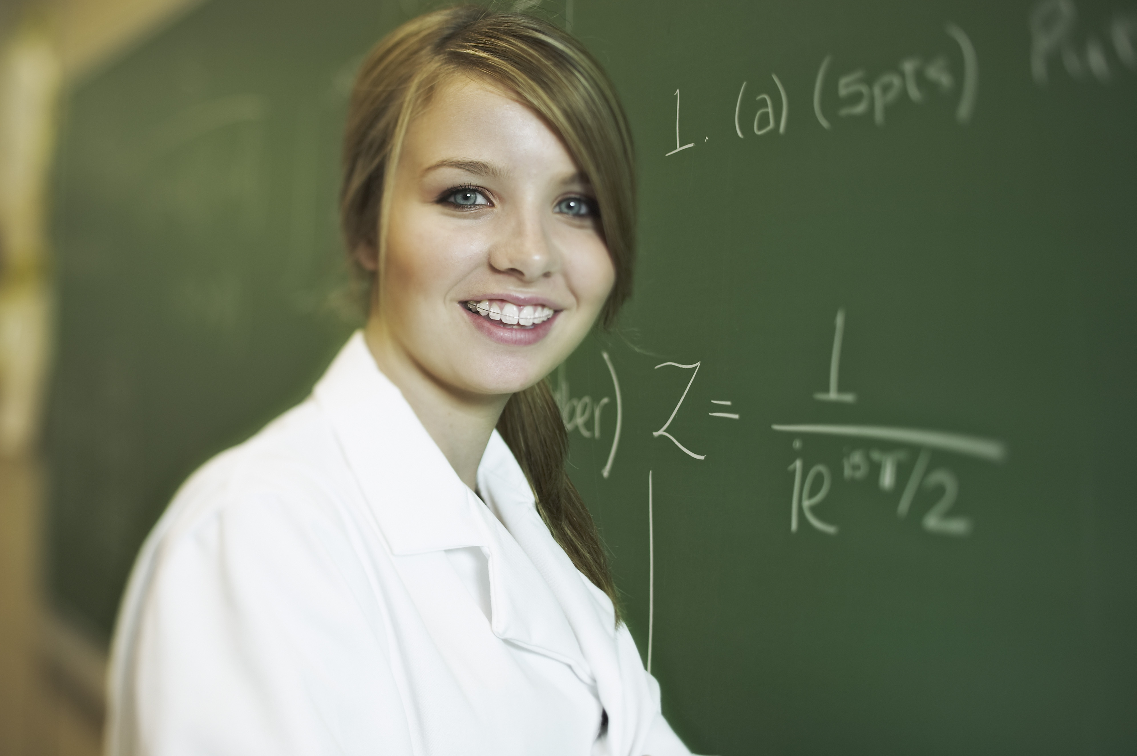 Smiling teenage girl standing in front of chalkboard